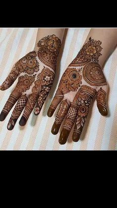 two hands with henna tattoos on them, one is brown and the other is white