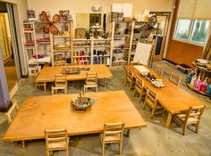 an empty classroom with wooden tables and chairs in the center, filled with children's toys