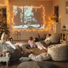 three children are sitting on the floor in front of a large screen with christmas lights