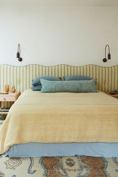 a large bed sitting in a bedroom next to a wall with two lamps on it