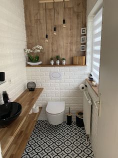 a white toilet sitting inside of a bathroom next to a wooden counter and shelf filled with potted plants