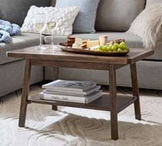 a tray with grapes, cheese and crackers sits on a coffee table in front of a couch