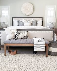 a bed with pillows and blankets on top of it in a bedroom next to two baskets