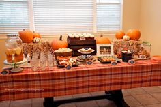 a table topped with lots of desserts and drinks next to a window filled with pumpkins