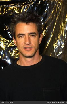 a man standing in front of a gold foiled wall with his eyes closed and looking at the camera