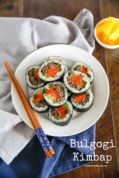 a white plate topped with sushi next to chopsticks