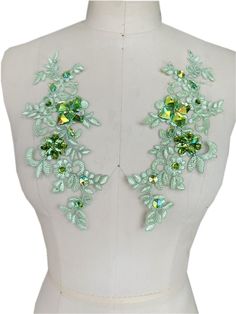 a white mannequin with green flowers and leaves on it's back side