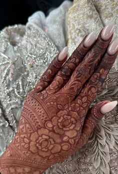 a woman's hands with hennap on her hand and nails in the middle