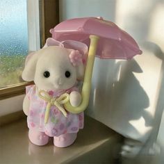 a stuffed animal holding an umbrella next to a window