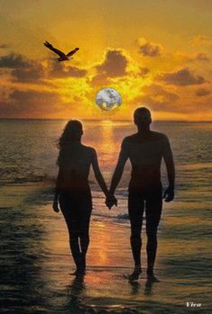 two people holding hands walking on the beach with sunset in the background and spanish quote