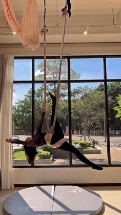 a woman doing aerial acrobatics in front of a large window