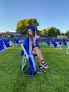 a woman sitting on top of a lawn chair wearing a graduation gown and holding a diploma