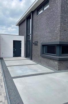 two black doors are on the side of a gray brick building with grey and white tiles