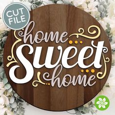 a wooden sign with the words home sweet home on it and some flowers around it