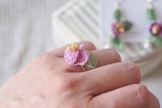 a person wearing a ring made out of tiny crochet flowers on their fingers