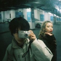 a man taking a selfie with a camera in front of his face while another woman looks on