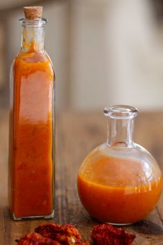 a glass bottle filled with red sauce next to a small container full of hot sauce