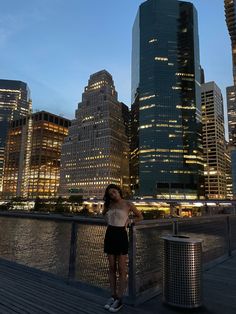 a woman standing on top of a wooden deck next to tall buildings in the city