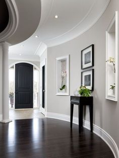 an empty hallway with pictures on the wall and a black table in front of it