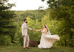 a bride and groom holding hands in the woods