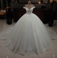 a white ball gown with sequins on the skirt is displayed in front of a mannequin