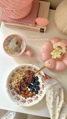 a bowl of cereal with blueberries and almonds in it on a table next to some books