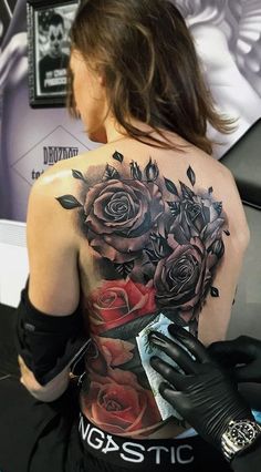 a woman with tattoos on her back is holding a piece of paper in her hand