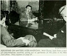 black and white photo of three men sitting at a table with papers in front of them