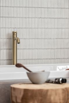 a white bowl sitting on top of a wooden table next to a sink and faucet