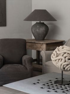 a living room filled with furniture and a lamp on top of a wooden table next to a chair