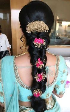 a woman with long black hair wearing a blue sari and pink flowers in her hair