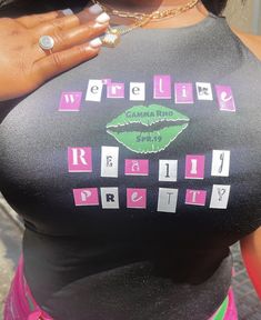 a woman wearing a black shirt with pink and green letters on the bottom that says,