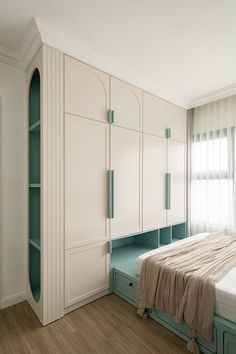 a bedroom with white cabinets and a bed in front of a window on the wall