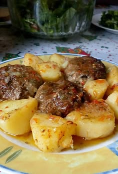 meatballs and potatoes are served on a yellow and blue plate with green lettuce