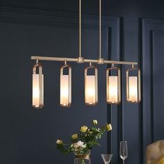 a chandelier hanging over a dining table with flowers and wine glasses on it