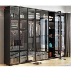 a walk in closet with glass doors and clothes hanging on the shelves, next to a window