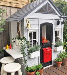 a small garden shed with potted plants and stools on the outside patio area