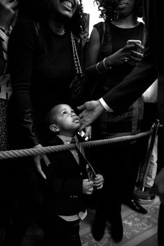 a man in a suit and tie is being handed something by a woman who is holding the hand of a young boy