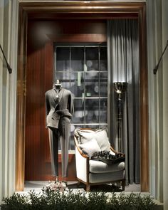 a mannequin dressed in a suit and tie next to a chair