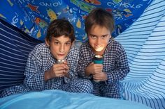 two young boys are playing with lights in their bed