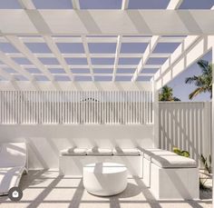 an outdoor seating area with white furniture and palm trees