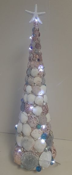 a christmas tree made out of seashells with a star hanging from the top