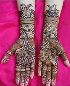 two hands with henna designs on them, one is showing it's intricate design