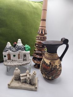 three decorative vases sitting on top of a table next to a pillow and other items