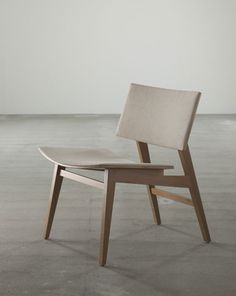 a wooden chair sitting on top of a cement floor next to a white wall in an empty room