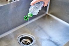 a person is washing their hands in a stainless steel sink with a green spout