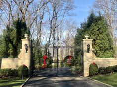 an iron gate with two wreaths on it and some trees in the back ground