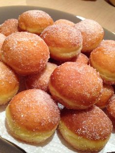 a plate full of sugar covered donuts on a table