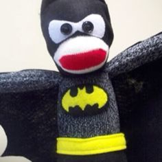 a stuffed toy with a bat costume on it's chest and eyes are shown in front of a white wall