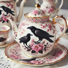 the tea set is decorated with black birds on pink flowers and gold trimmings